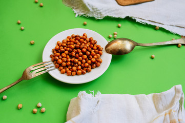 white plate with ready-baked chickpeas on a cotton vintage napkin and an old metal fork and spoon...