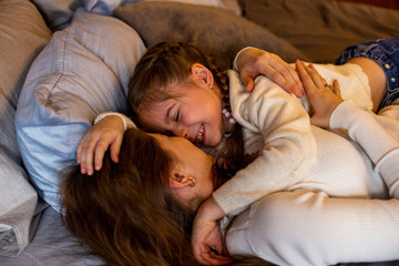 horizontal closeup portrait of a six year old girl playing in bed with her mom