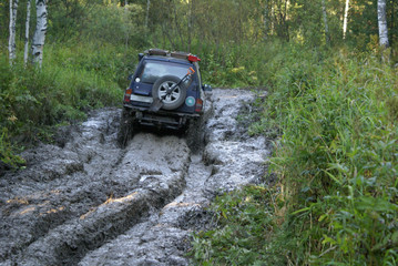 Obraz na płótnie Canvas the car goes off road through deep mud in the forest