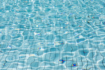 Sun reflection in clear clean and bright blue water of swimming pool, Shining blue water ripple background, Aqua texture, pattern