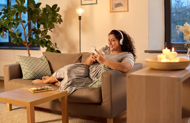 technology, people and leisure concept - happy young woman in headphones listening to music on...