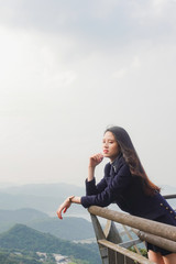 Portrait of a beautiful, young and fashionable Thai Asian woman posing over a beautiful landscape
