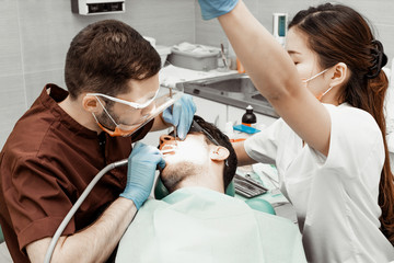 A young male dentist doctor treats a patient. Medical manipulations in dentistry, surgery....