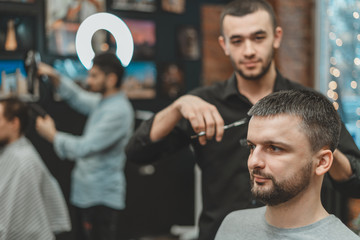 Haircut at the hairdresser. Barber cuts the hair on the client's head. The process of creating...
