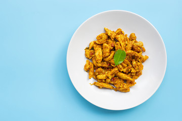 Chicken with yellow curry paste on blue background. Copy space