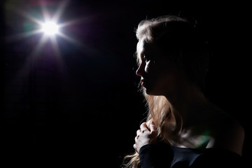 Portrait of a girl illuminated by the contour light of a flash on a black background