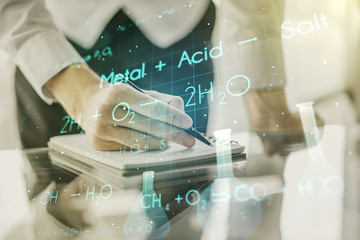 Creative chemistry hologram with man hand writing in notepad on background, pharmaceutical research concept. Multiexposure