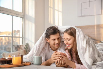 Morning of young couple having breakfast in bed