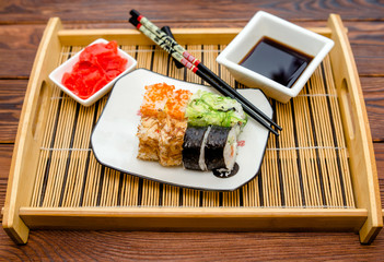 Several sushi on a white plate standing on a brown background