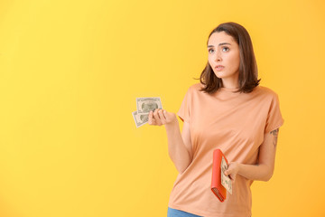 Sad young woman with wallet and money on color background