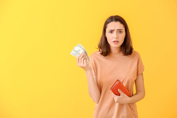 Sad young woman with wallet and money on color background