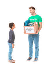 Volunteer with donations for orphans and little boy on white background