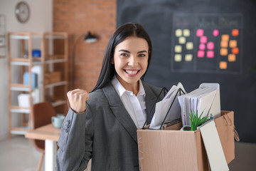 Happy fired woman with personal stuff in office
