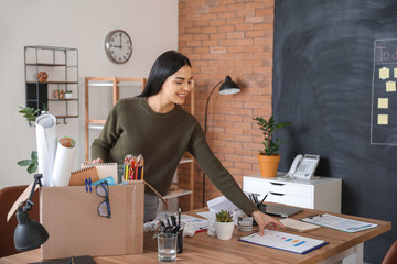 Happy fired woman packing personal stuff in office