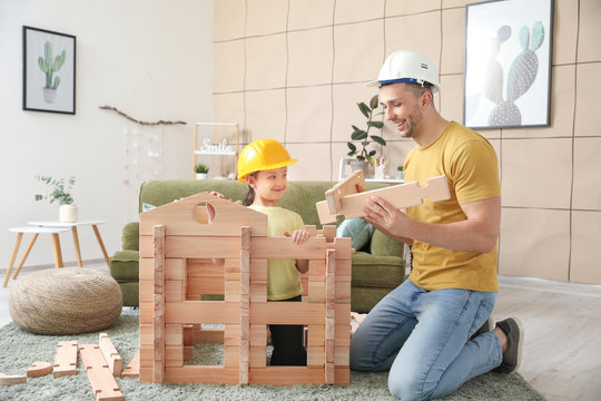 Father And Little Daughter Dressed As Builders Playing With Take-apart House At Home