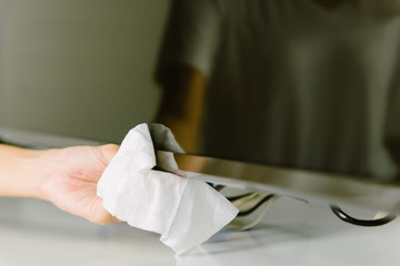 Asian woman cleaning television with disinfection wipe.