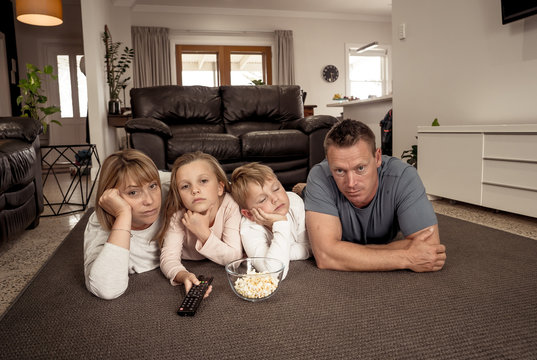 COVID-19 Outbrek. Bored Family Confined To Their Home Watching Tv During Coronavirus Lockdown