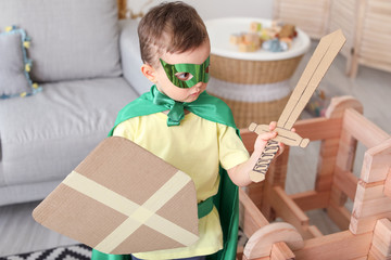 Little boy dressed as knight playing with take-apart house at home