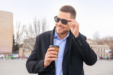 Handsome man with cup of coffee outdoors