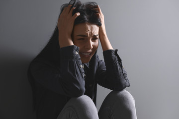 Scared female victim on grey background. Concept of violence