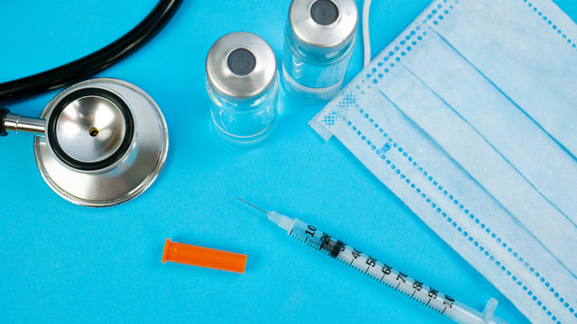 Syringe for Insection, Yellow tablets and Stethoscope As Background. Vaccine and paper notebook. Concept of clinic or hospital, health care or doctor. Medical Equipment on blue surface
