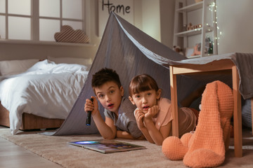 Scared little children reading bedtime story at home