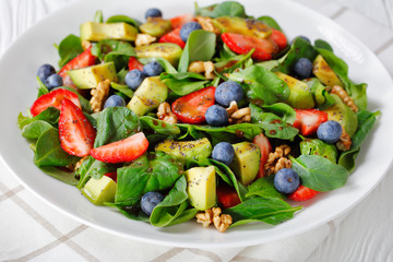 close-up of spinach avocado walnuts berries salad