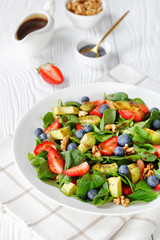 close-up of spinach avocado walnuts berries salad