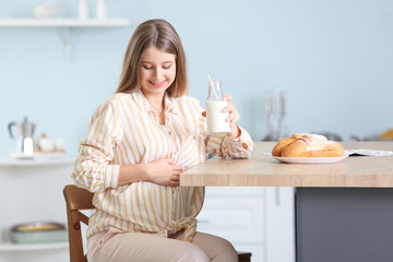 Obraz na płótnie Canvas Beautiful pregnant woman drinking milk in kitchen
