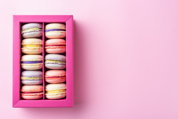 Colorful macaroons and flowers. Sweet macarons in gift box. Top view