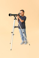 Little African-American boy with telescope on color background