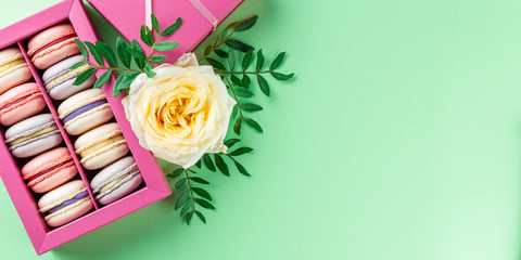 Colorful macaroons and flowers. Sweet macarons in gift box. Top view