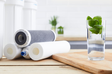 A glass of clean water with osmosis filter and cartridges in a kitchen interior. Concept Household...