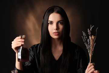 Female alchemist with potion on dark background
