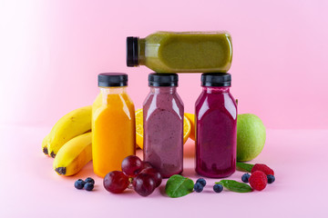 Colourful healthy smoothies and juices in bottles on color background with copy space.