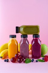Colourful healthy smoothies and juices in bottles on color background with copy space.