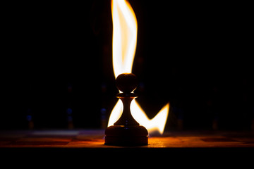 chess board on fire with figures in the dark, front and background blurred with bokeh effect