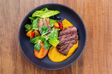 Juicy steak medium rare beef with green salad on plate. Top view, flat lay