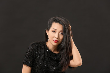 Fototapeta premium Young Asian woman with beautiful hair on dark background