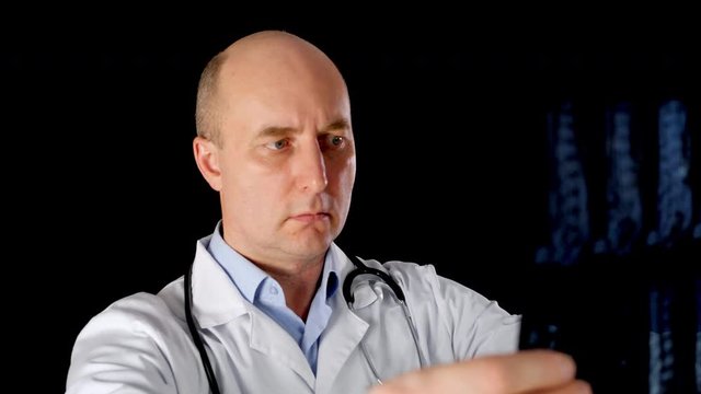 Confident radiologist examine holding x-ray. Professional medical worker inspecting x-ray on black background. Medicine concept