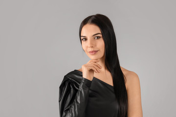 Young woman with beautiful healthy hair on grey background