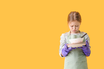 Sad little girl with dirty dishes on color background