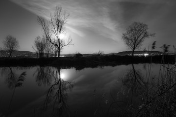 Moon and trees reflecting on the Trasimeno lake surface at night