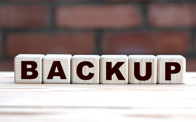 concept word BACKUP on cubes against the background of a brick wall