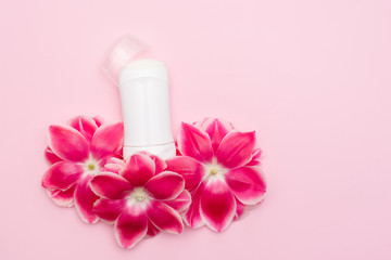 Obraz na płótnie Canvas body antiperspirant deodorant with flowers on pink background with a copy space