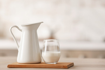 Glass and jug of fresh milk on table