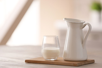 Glass and jug of fresh milk on table