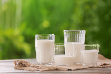 Glasses of fresh milk on table outdoors