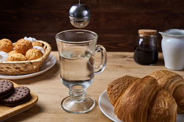 Hot tea put on table, drink breakfast in the morning day, breakfast with tea strainer and sweets on wooden table