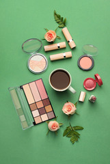 Makeup cosmetics with cup of coffee on color background